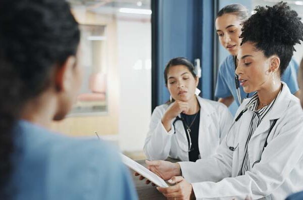 Doctors, nurse and women on clipboard in meeting, collaboration or teamwork for hospital planning, medical or life insurance. Talking, leadership and healthcare workers on paper in diversity research.