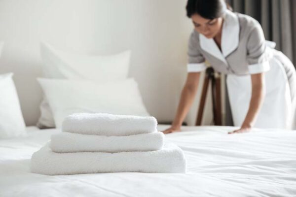 Young hotel maid making the bed with clean fresh towels